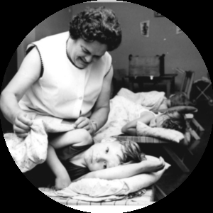 Image of a woman tucking a child into bed